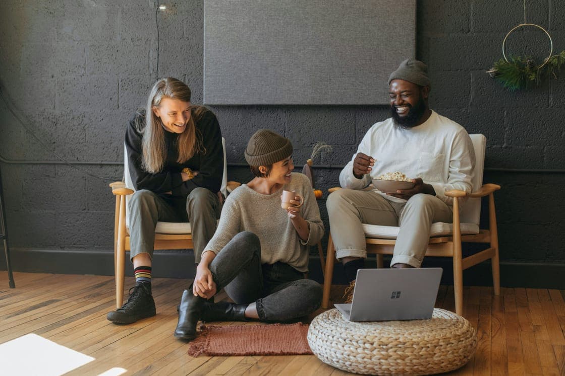 Three coworkers laughing together in a dark-walled room