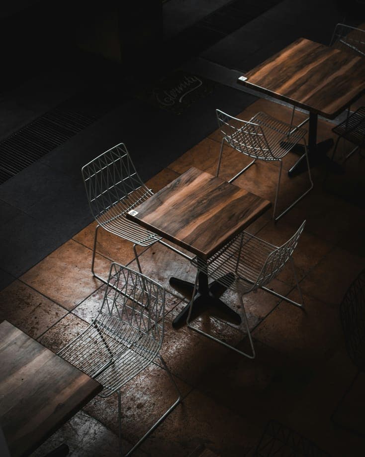 Wooden tables and metal chairs seen from above in a dark room