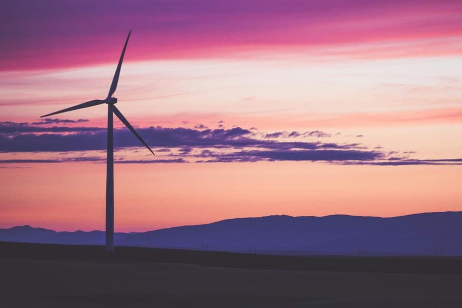 A wind turbine against a pink and purple sunset sky