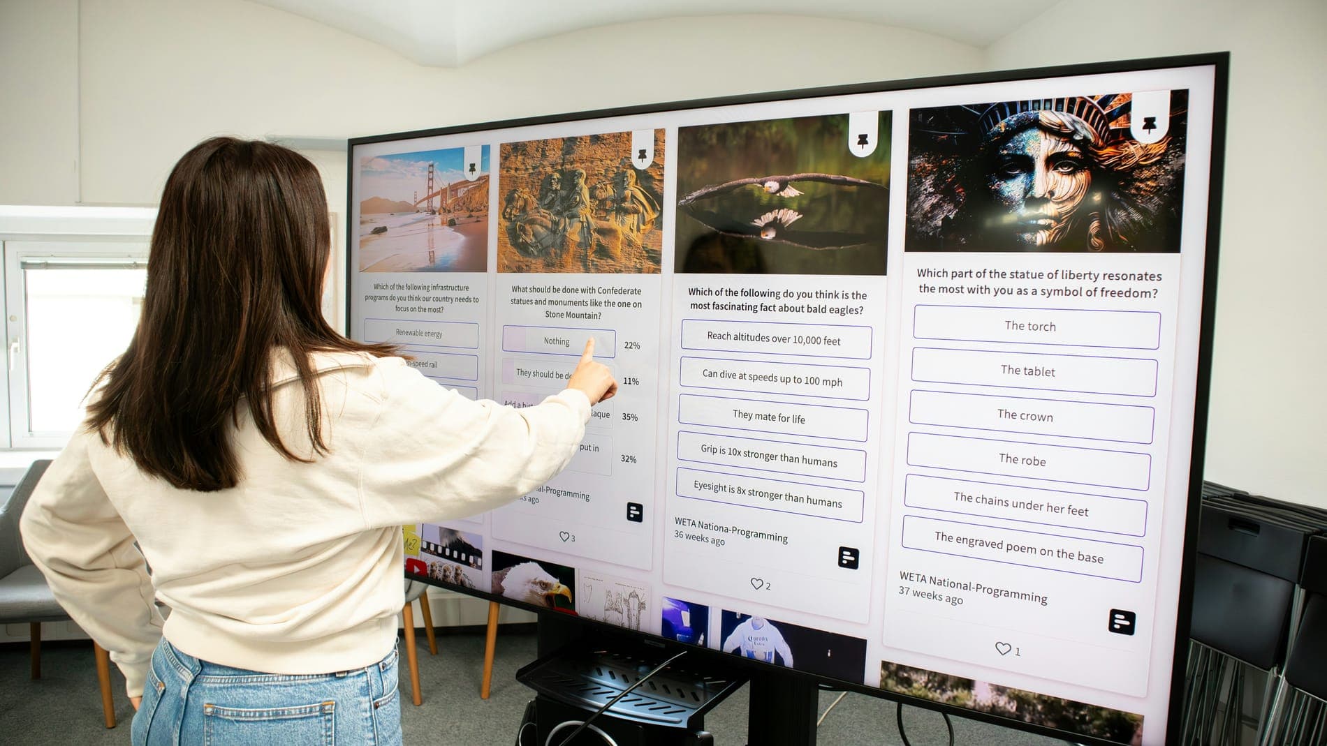 A woman tapping a large touchscreen that shows a quiz