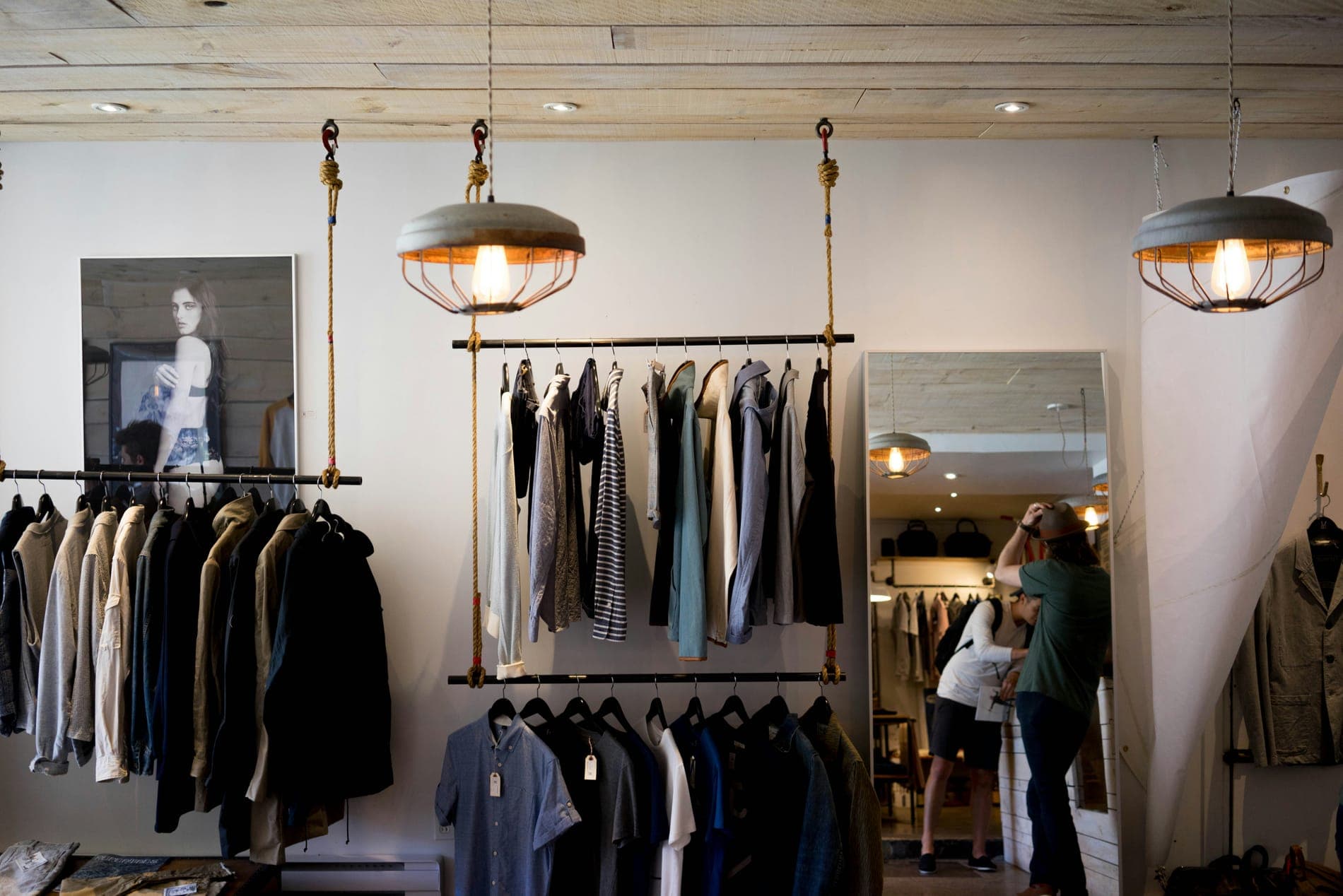 A clothing shop with a rail of jackets and a framed portrait on the wall