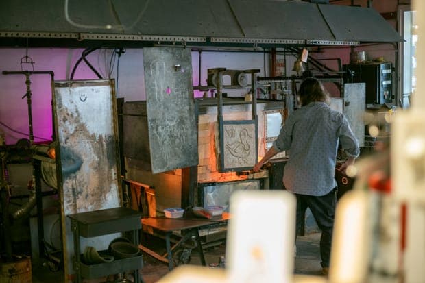 A man working at a fire in a workshop with a pink glow