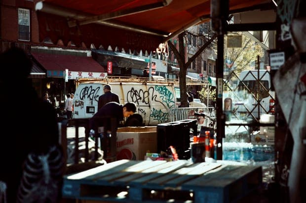 A busy street corner with a graffiti-covered van and a red awning