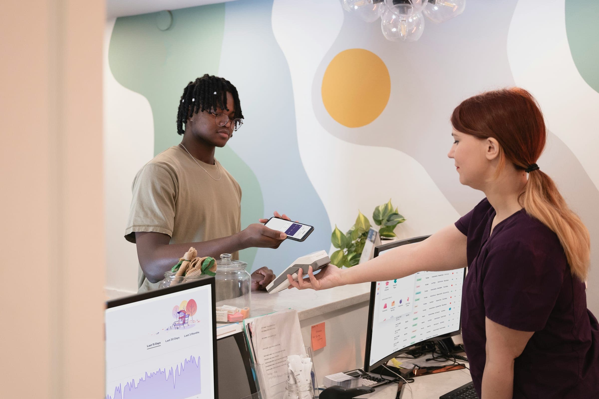 A customer paying a receptionist with a phone at a clinic desk