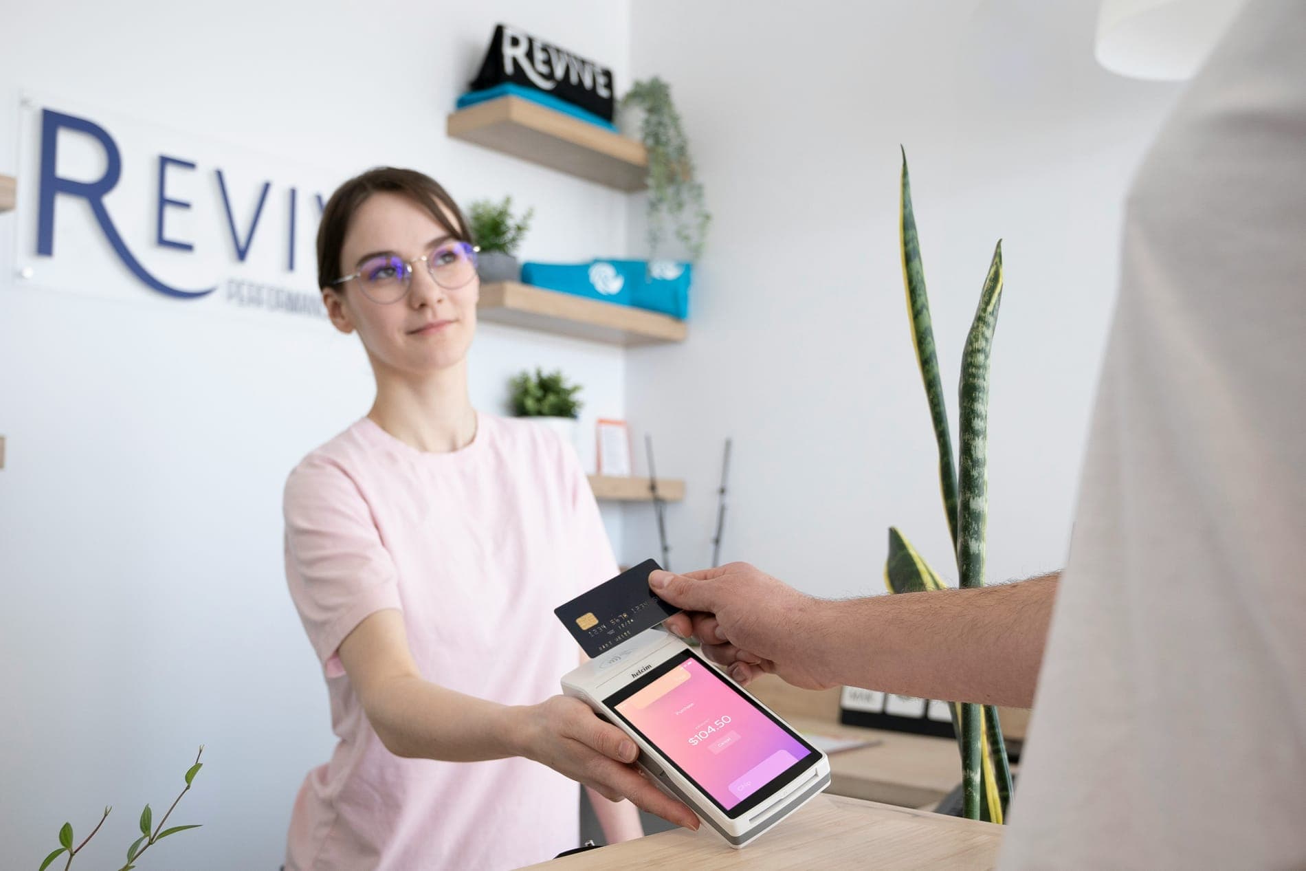 A smiling woman holding a card reader toward a customer
