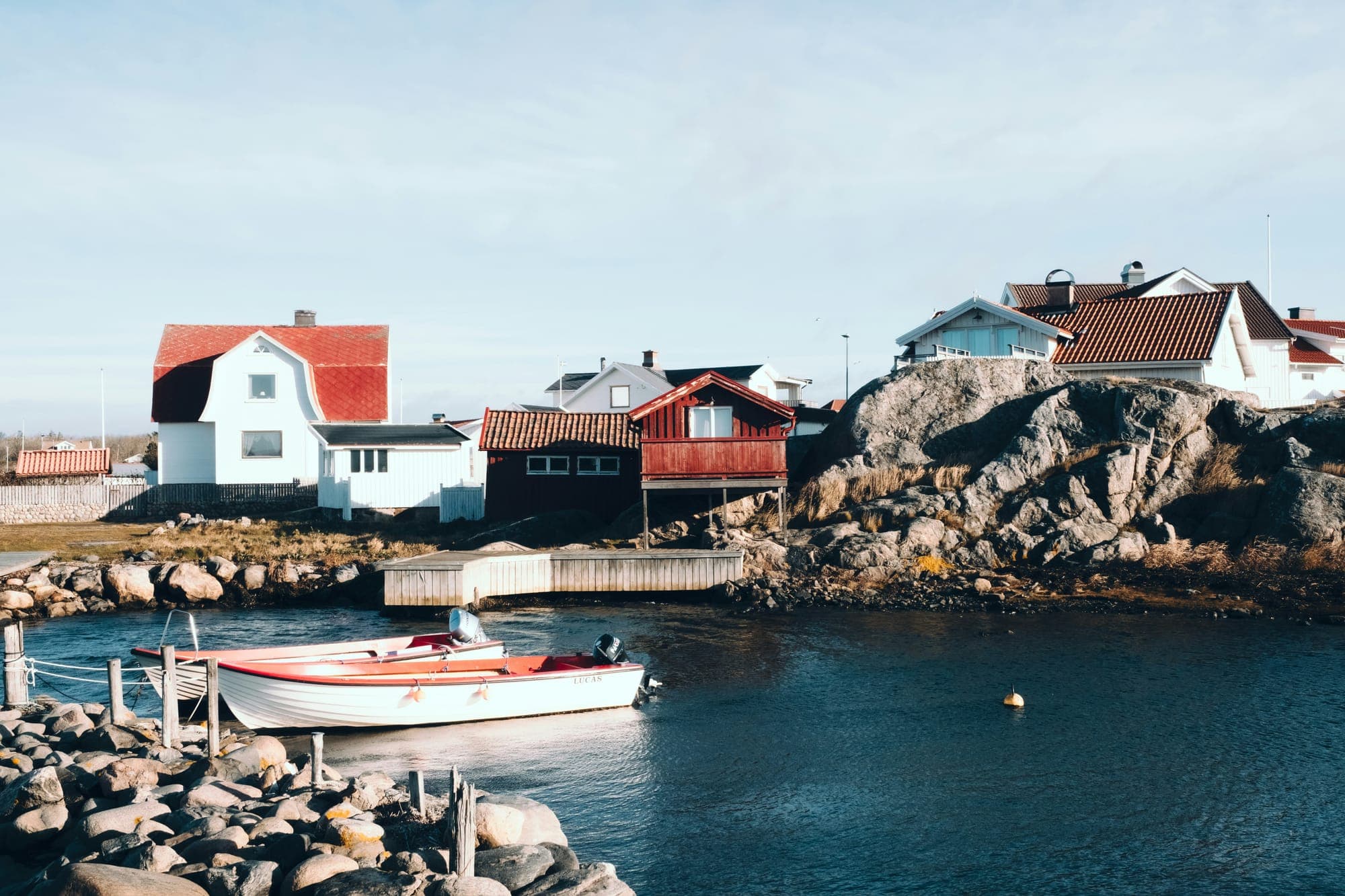 White and red houses on a rocky harbour with a moored boat