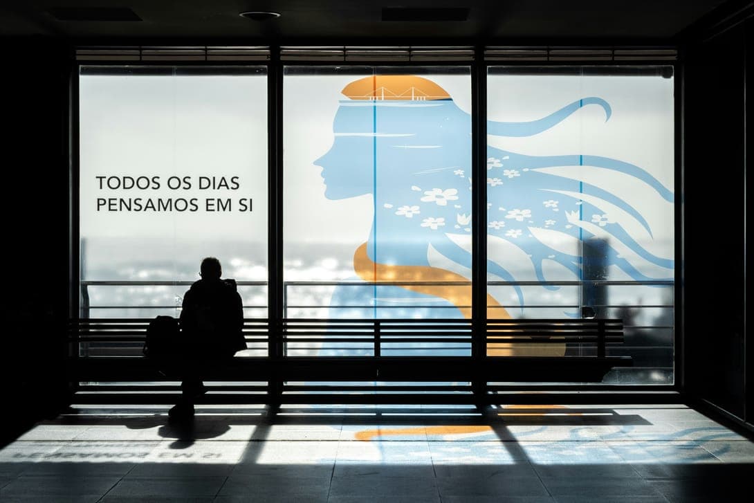 A person silhouetted in front of a large window with a printed mural