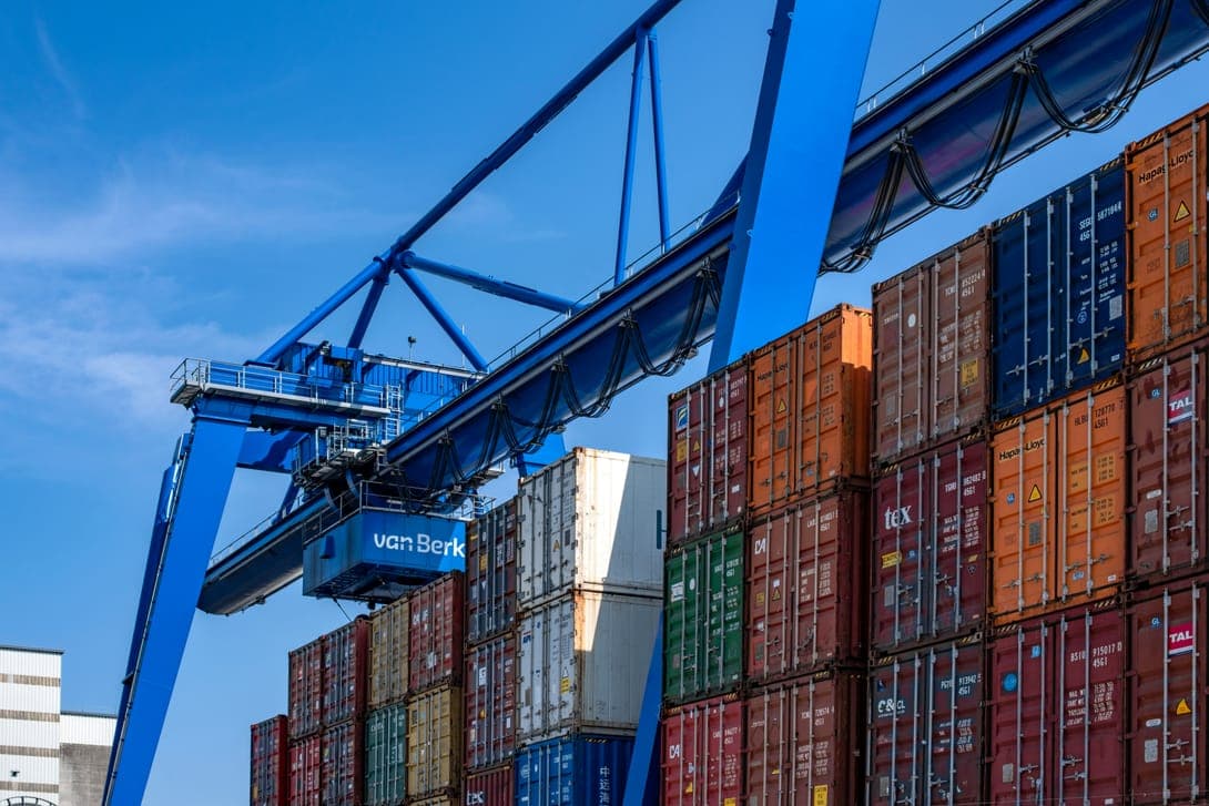 A blue gantry crane over stacked shipping containers
