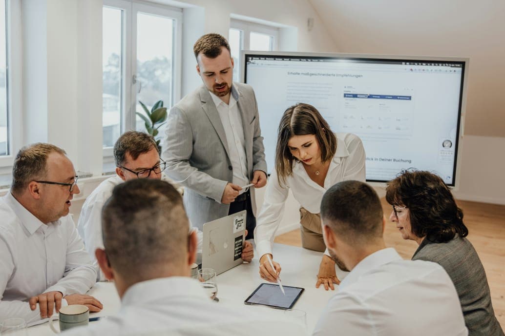 A team gathered around a white table reviewing a tablet