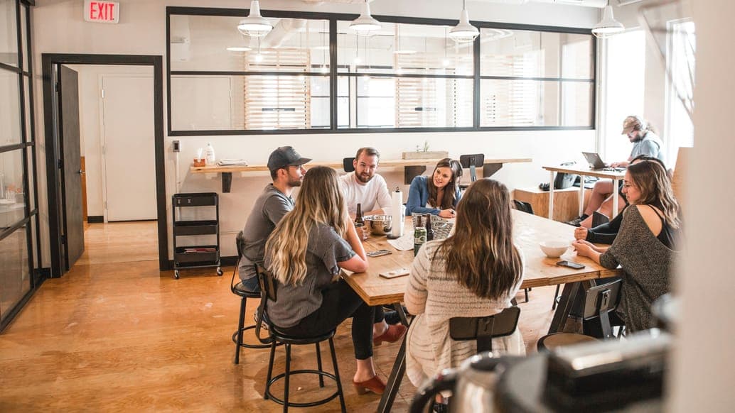 A group around a long wooden table in a loft office