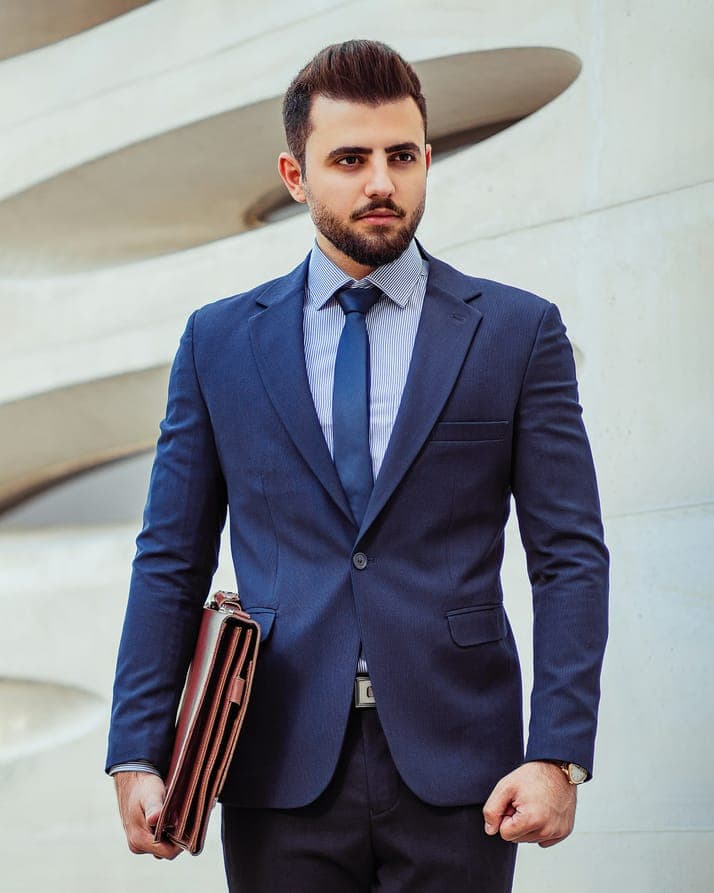 A man in a blue suit holding a leather folder
